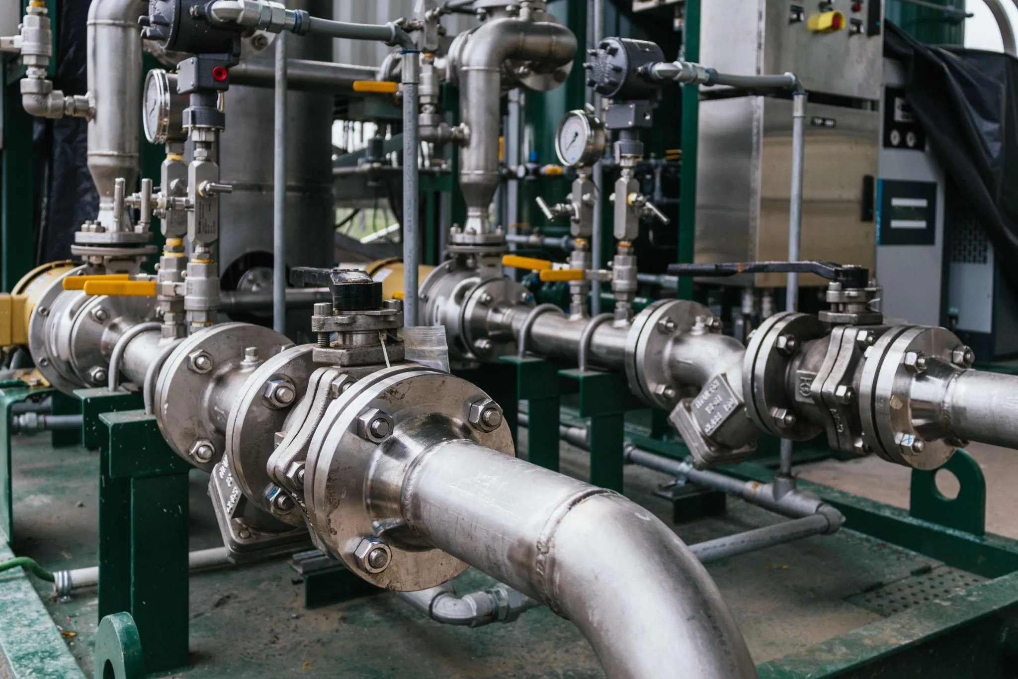 Stainless steel pipework on an industrial skid, with flanged ball valves and pressure gauges